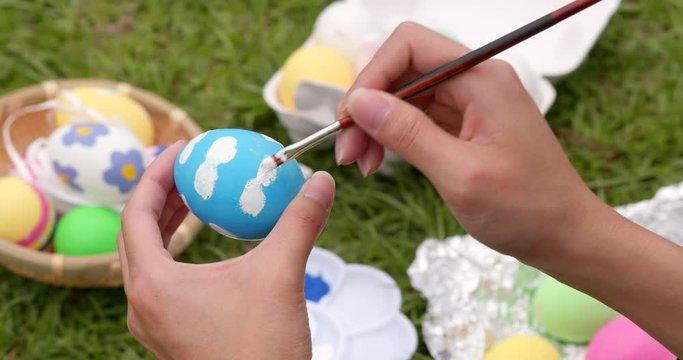 Painting on egg for Easter holiday at outdoor green lawn