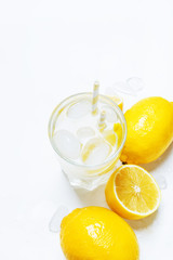 Summer refreshing drink, cold water with ice and lemon, white background, top view
