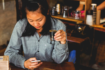 Asian business young girl using smartphone and holding coffee cup in coffee shop.