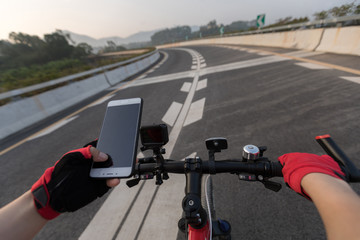 Cyclist using smartphone for navigation when riding mountain bike on highway