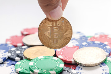hand holding bitcoin and pile of casino chips on white background