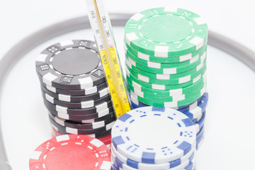 Thermometer and pile of casino chips on white background