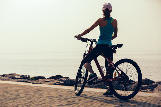 Woman cyclist riding mountain bike on seaside