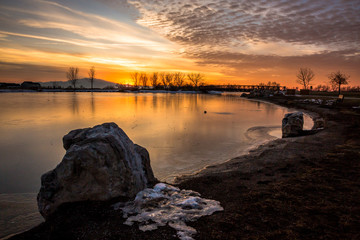 Sunset over a pond with mountains in background creating a serene peaceful feeling