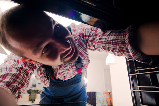 Handyman searching the problem in the oven