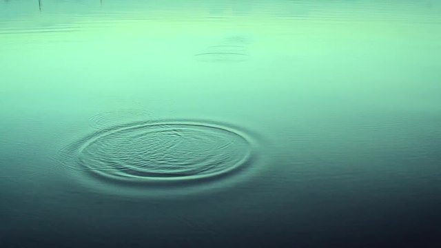 Stone skipping on calm smooth water surface. Beautiful view of skimming a small flattened rock thrown and bouncing off water surface across body of water many times in water
