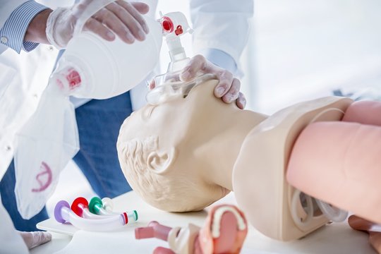 Doctor practising bag-valve-mask ventilation on dummy