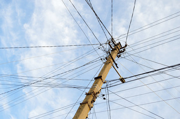 Many wires strained on one power line pole on the background of the sky