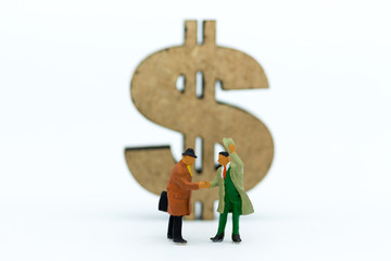 Miniature people : Two businessmen make a deal, with currency to background. Image use for commitment, finance, investment and partnership concept.