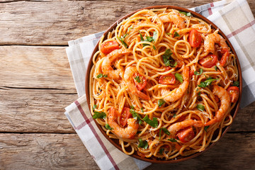 Spicy spaghetti with shrimps in tomato sauce close-up. Horizontal top view from above