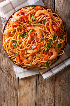 Spicy spaghetti with shrimps in tomato sauce close-up. Vertical top view from above