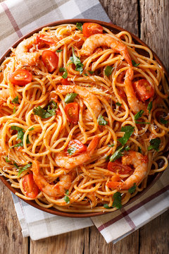 Portion of spaghetti with shrimps, parmesan cheese with tomato sauce close-up on a plate. Vertical top view