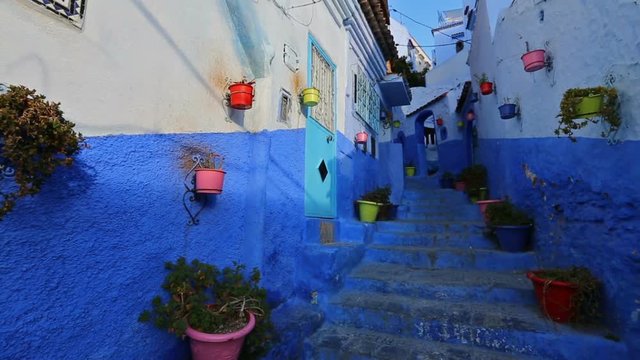 Panorama of traditional old blue street with color pots inside Medina of Chefchaouen, Morocco