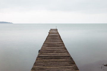 Long exposure first person view of a pier on Trasimeno lake (Umbria), with perfectly still water