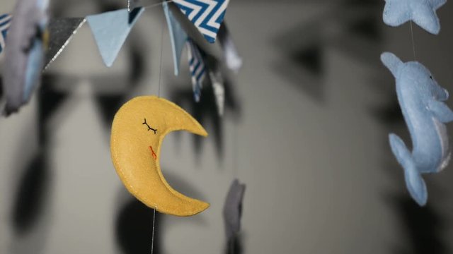baby mobile with blue hand-stitched animal and bird toys with yellow moon on white wall background