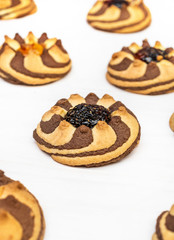 Rows of sweet cookies with jam on the white wooden table.