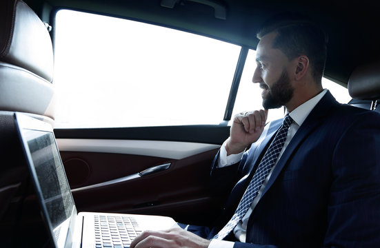 Businessman typing text on laptop while sitting in car