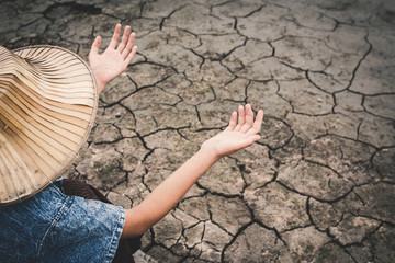 Sad girl praying for the rain on cracked dry ground , Concept drought and shortage of water crisis,...