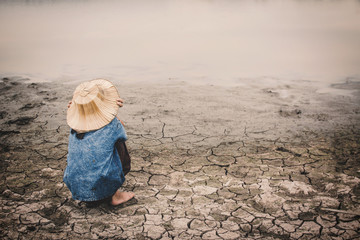 Sad girl and exhausted on cracked dry ground, Concept drought and shortage of water crisis