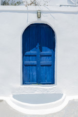 Traditional Greek architecture, a blue painted doorway with whitewashed walls.  Taken on the island of Santorini. 