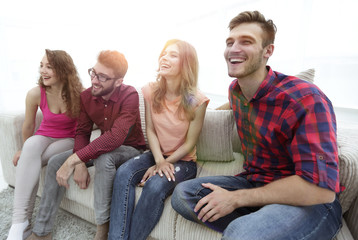 group of smiling young people sitting on the couch