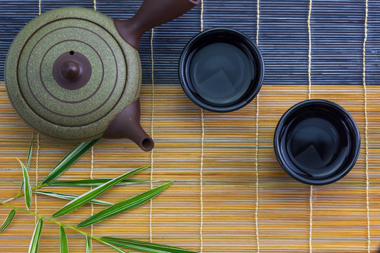Japanese hot tea pot with cup on bamboo mat, top view
