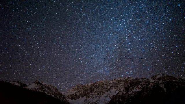 Time lapse video of Milky Way Galaxy moving over snowy mountains.