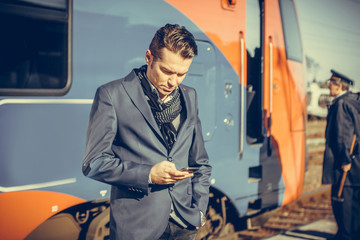Fototapeta na wymiar Businessman checking schedule on mobile phone at train station.