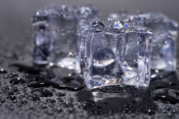 Three ice cubes with water drops isolated on black background