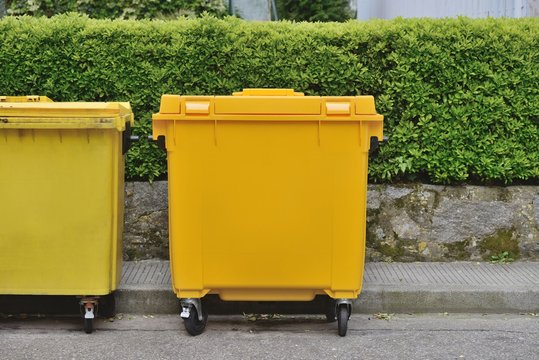 yellow plastic garbage can in the street