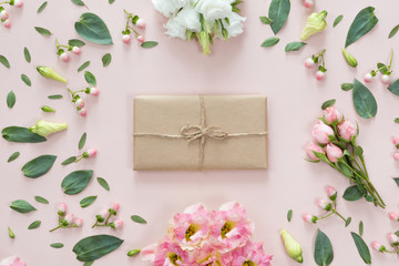 Flat lay of vintage gift box of Kraft eco paper with flower frame wreath on pink background, top view with copy space