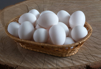 Chicken eggs in a basket on a wooden background