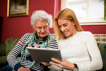 Two generation using tablet and smiling together