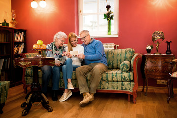 Grandparents and young girl looking old photos and talking about their youth