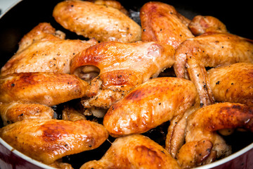 Closeup of baked chicken wings in baking pan. Selective focus
