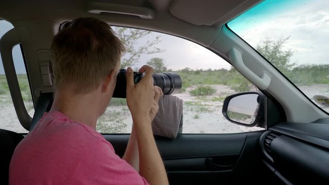 Man taking pictures of wildlife in Africa from car