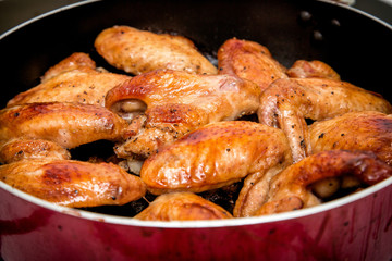 Closeup of baked chicken wings in baking pan. Selective focus