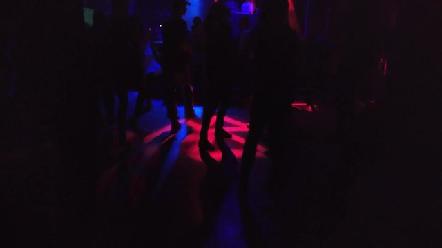 Silhouettes of the dancing people at a concert of DnB