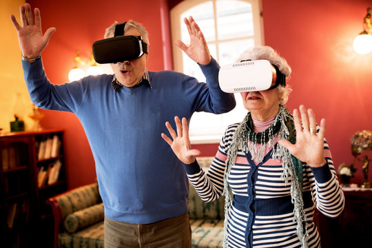 Funny shocked senior couple using virtual reality glasses - Powered by Adobe