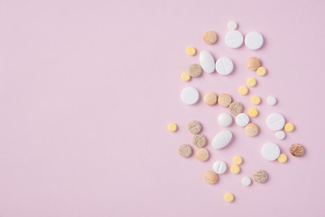 Different tablets and pills in the package and without it on a pink background