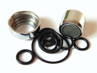 Details for plumbing close-up. Brass nut from the faucet. A metal aerator to save water. Nozzle  for faucet. Rubber sealing rings.