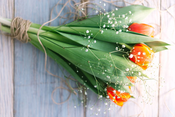 Blossoming tulips with a rope on a wooden light background