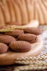 Delicate oatmeal cookies on a wooden background with spikelets.