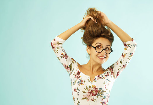 Funny pretty young woman in round glasses holding her hair up