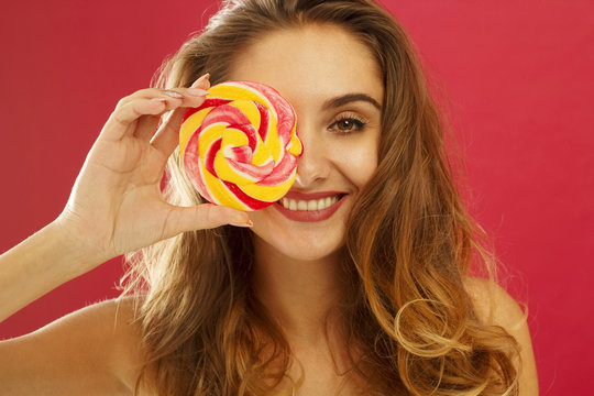 Portrait of a happy girl holding sweet candy over red background