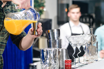 Unidentified barman pouring juice in a metal glass, shallow dof