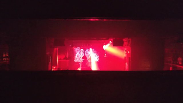 A view on the stage of an underground techno club with rays of red light