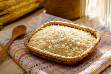 Uncooked basmati rice, extra long type, in a little plate on a towel put on a wooden table. Basmati rice is a base ingredient for many Asian Oriental recipes.