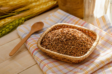 Grechka (buckwheat) in a little plate on a towel put on a wooden table. Grechka is used as food in most of the Eastern Europe countries