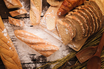 Fresh baked bread on dark wood table with copy space background  still life composition with wheat flour spread around with rice wheat.